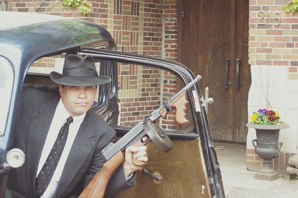 a man in a hat holding a gun in a car