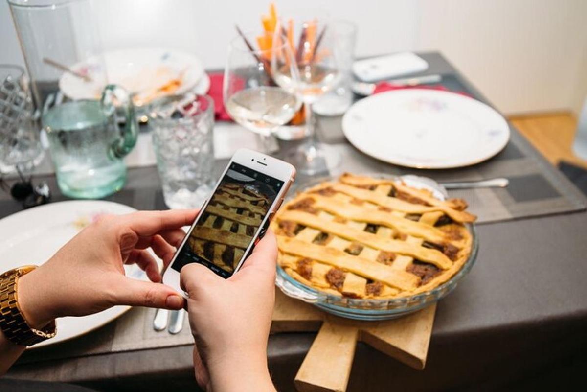 a person holding a cell phone in front of a pie