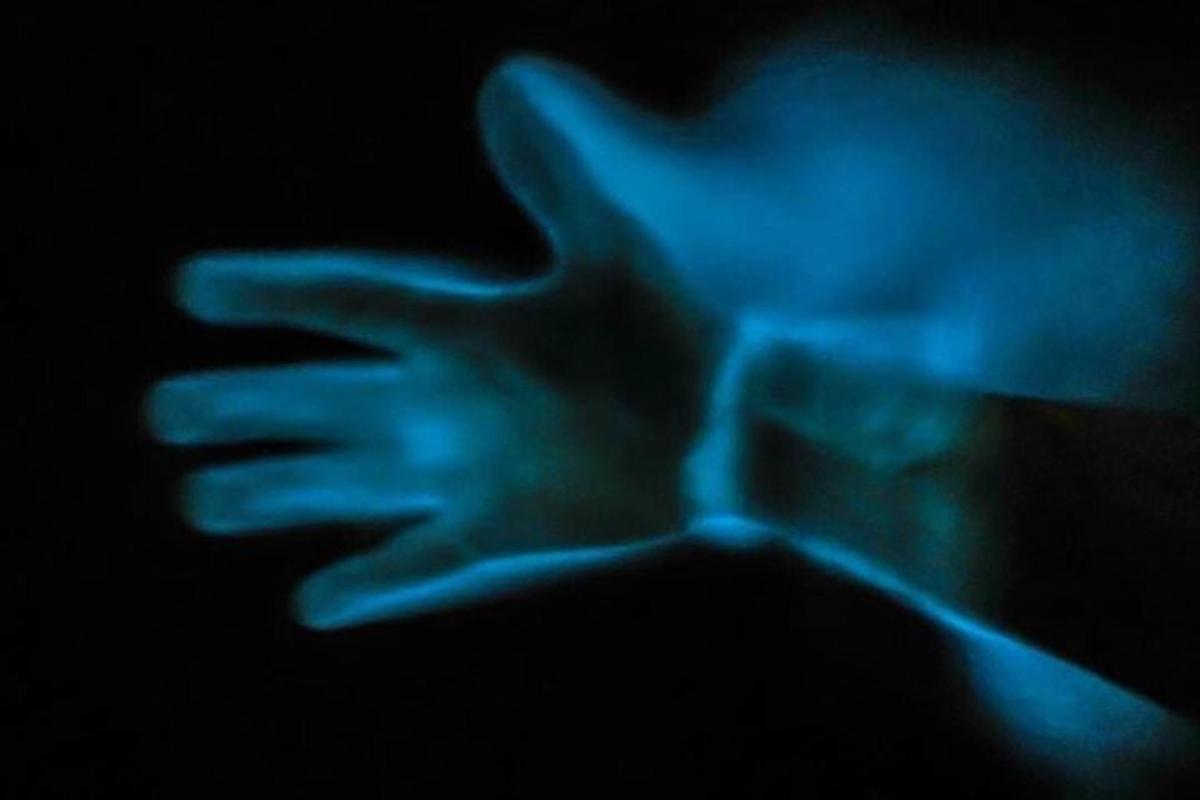 a person holding their hand up in the dark