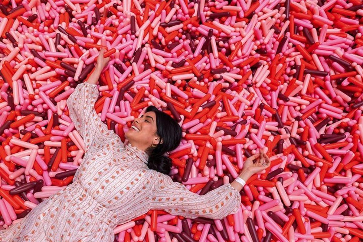 a woman laying in a large pile of red peppers