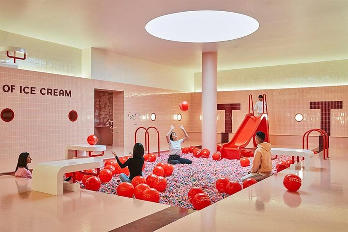 a group of children sitting in a play room with red balls