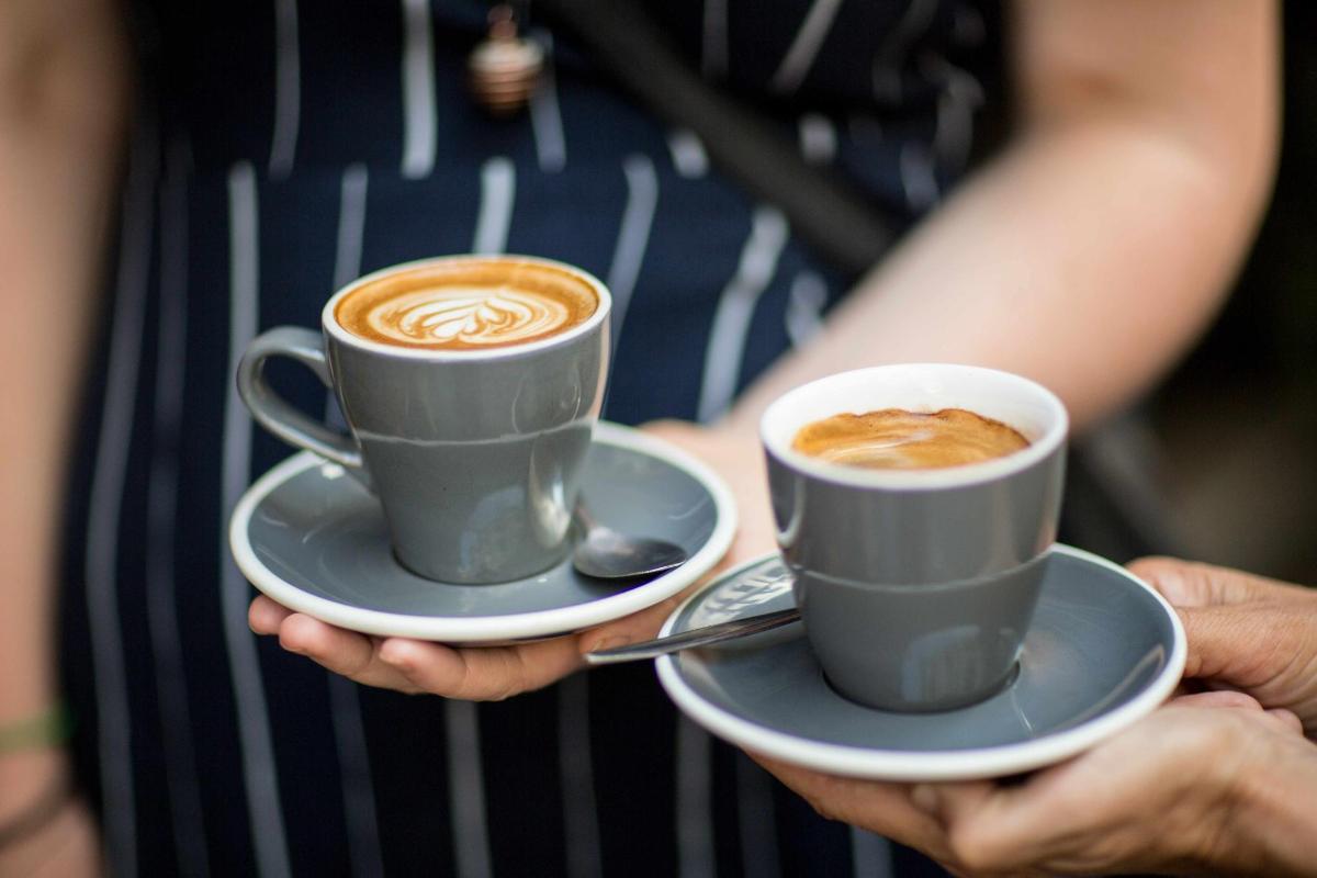 dues tasses de cafè assegudes en plats a les mans