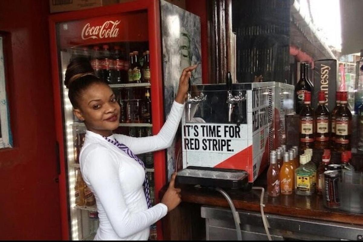 Una mujer sosteniendo un cartel frente a un enfriador de bebidas.