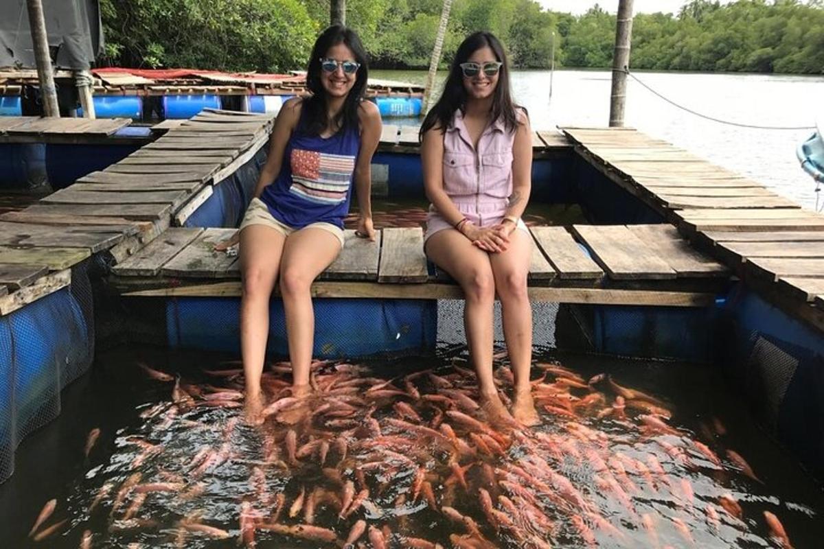 桟橋に魚の束を持って座っている二人の女の子