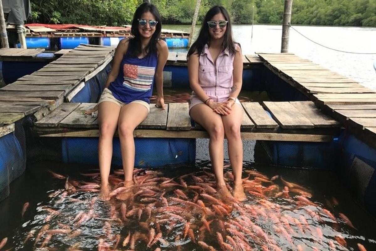 dua gadis duduk di jeti dengan sekumpulan ikan