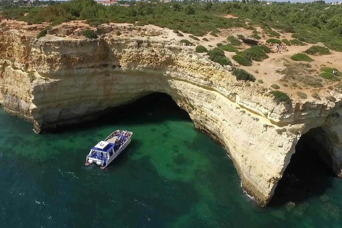 a boat in the water in front of a large rock bridge