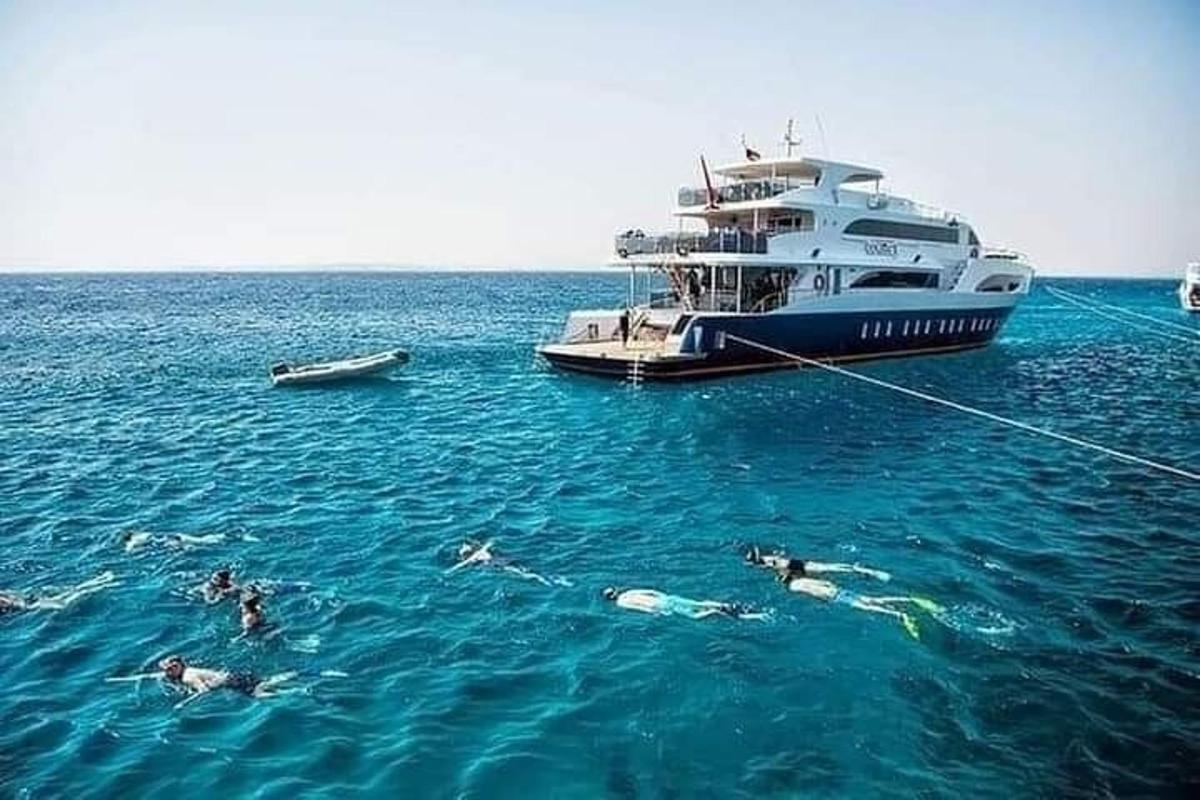 un grup de persones nedant a l'aigua al costat d'una barca