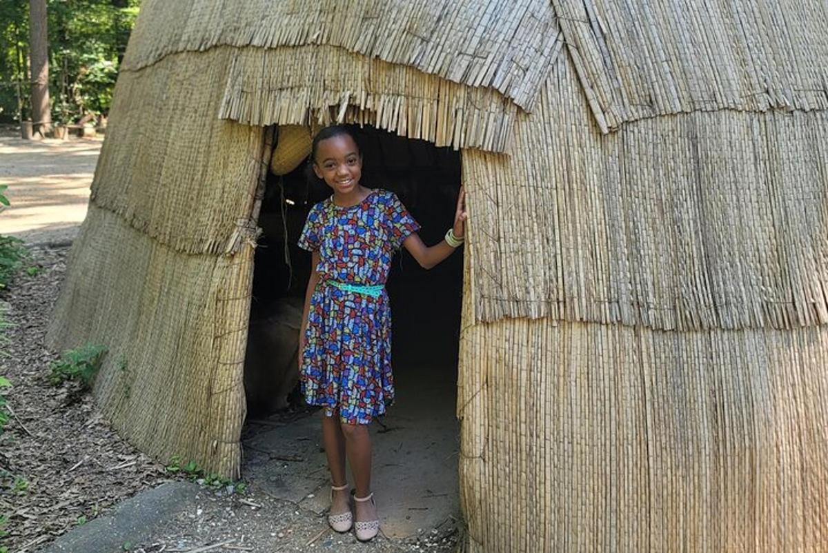 a young girl standing in a thatch hut