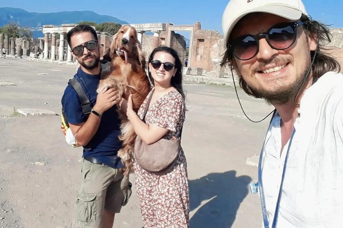 Δύο άνδρες και μια γυναίκα κρατούν ένα σκυλί στην παραλία