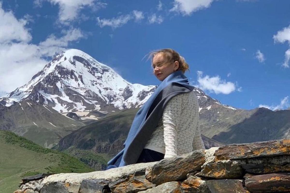 a woman standing on a wall with a snow covered mountain