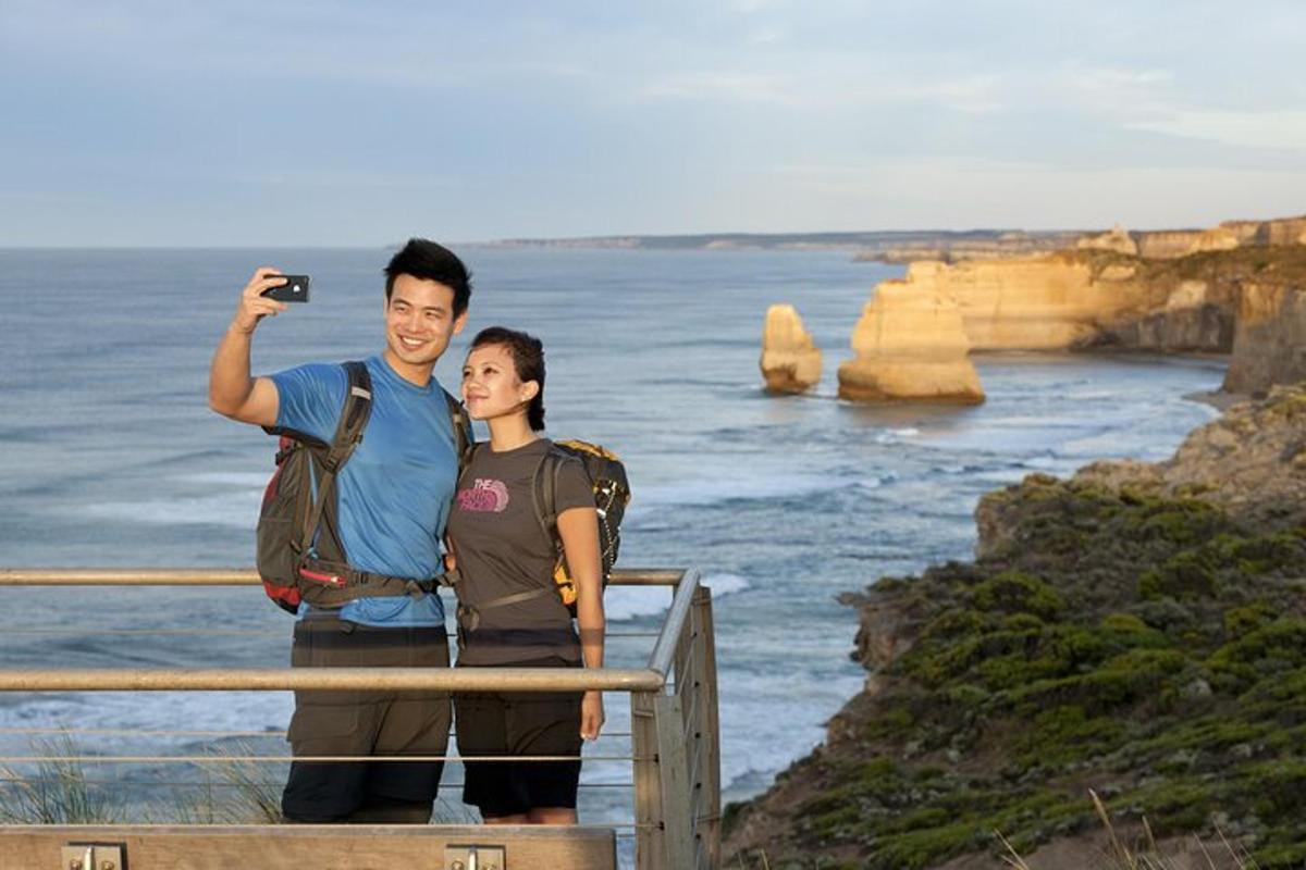 a man taking a picture of a woman taking a picture of the ocean