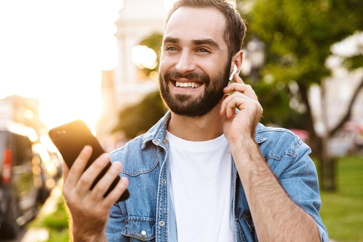 egy férfi mobiltelefonon beszél, miközben a kezében tartja a mobiltelefont