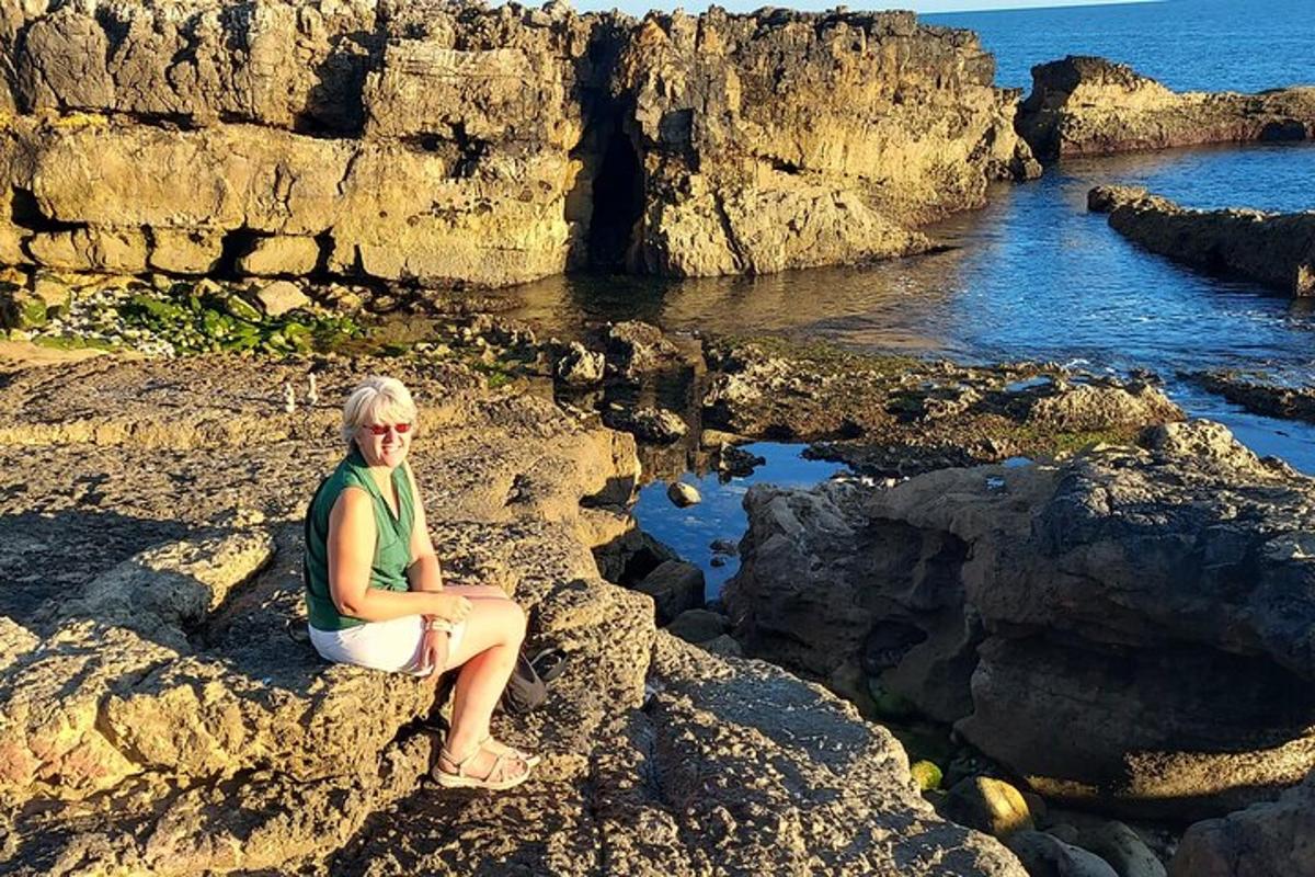 žena sedící na skalách poblíž oceánu