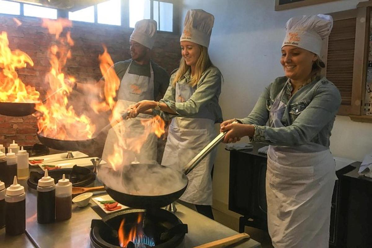 to kvinder og en mand i et køkken, der laver mad på en grill