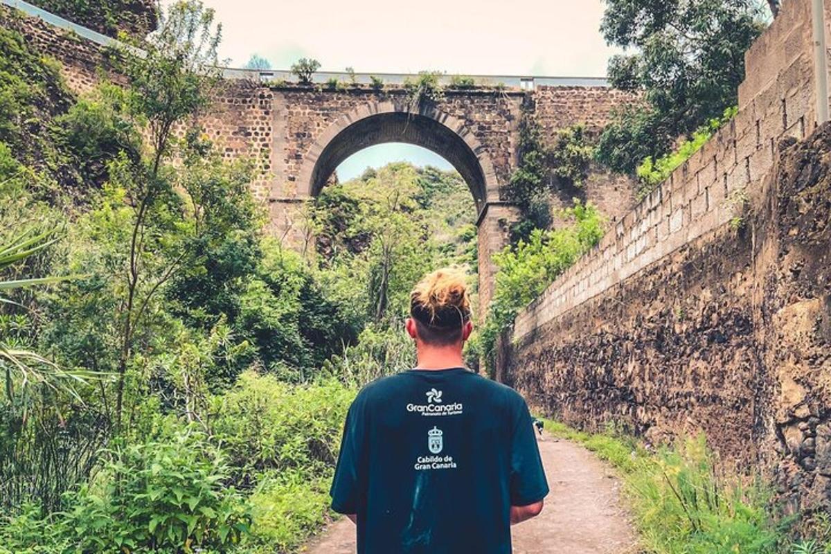 Ein Mann, der einen Feldweg vor einer Brücke entlanggeht