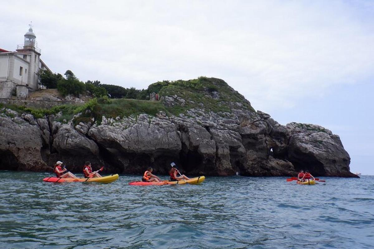 a group of people kayaking on the water near a rock formation