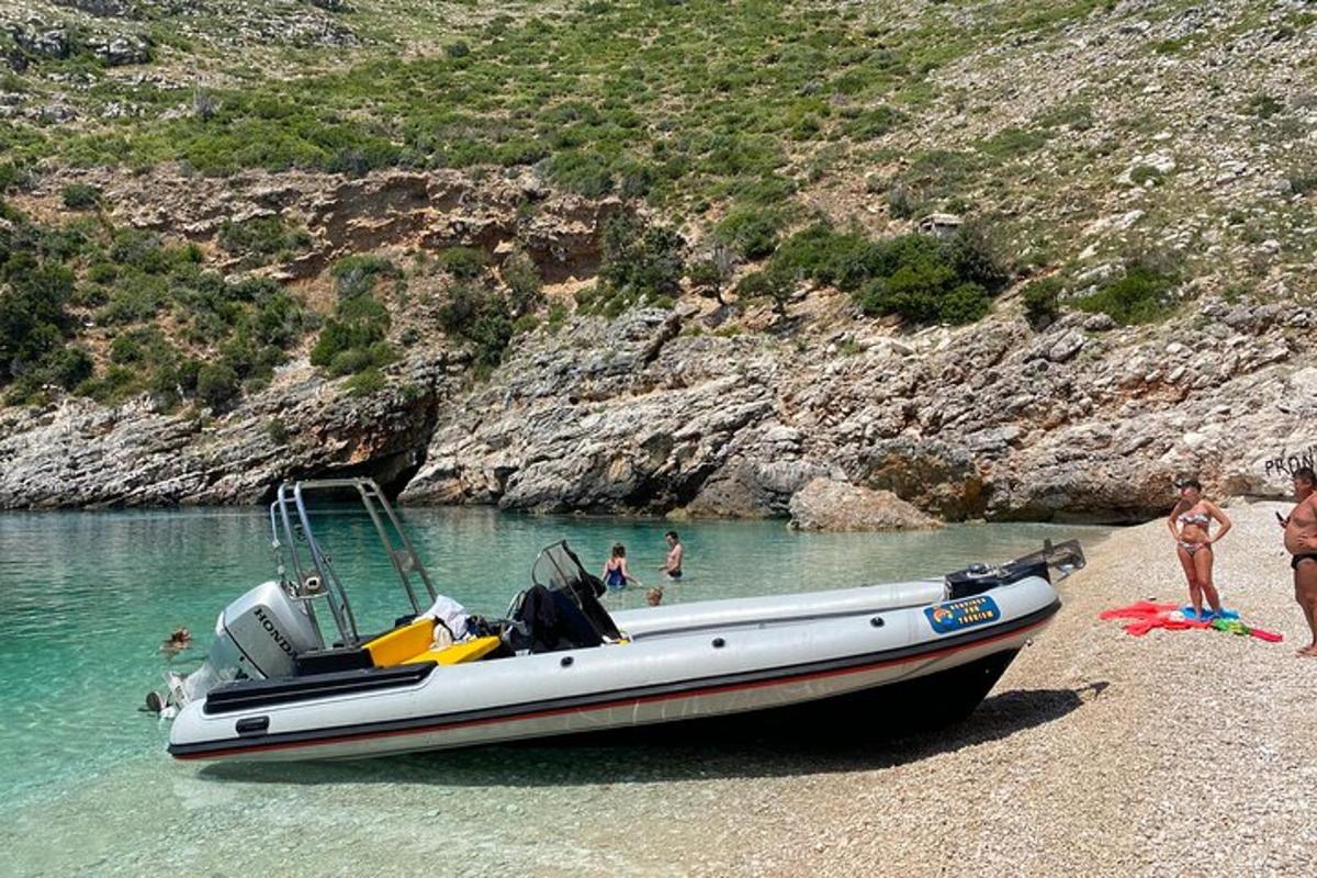 čoln, ki stoji na plaži, z ljudmi v vodi