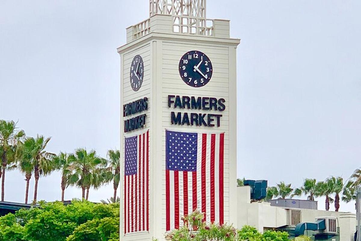 a clock tower with an american flag and a farmers market sign