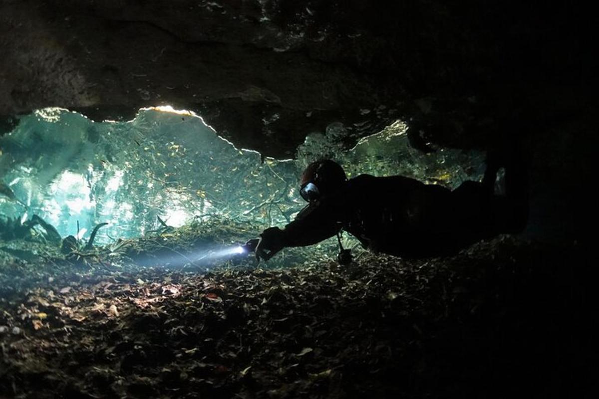 en person som knäböjer i en grotta med en ficklampa