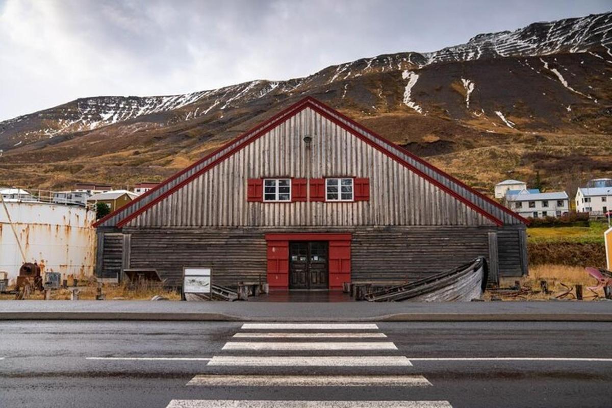 en låve med en rød dør foran et fjell