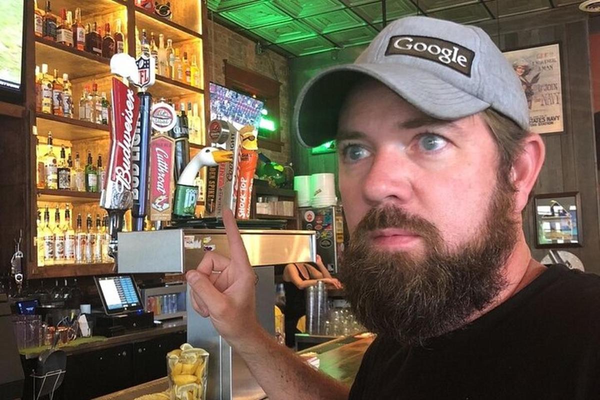 Un hombre con barba de pie en un bar.