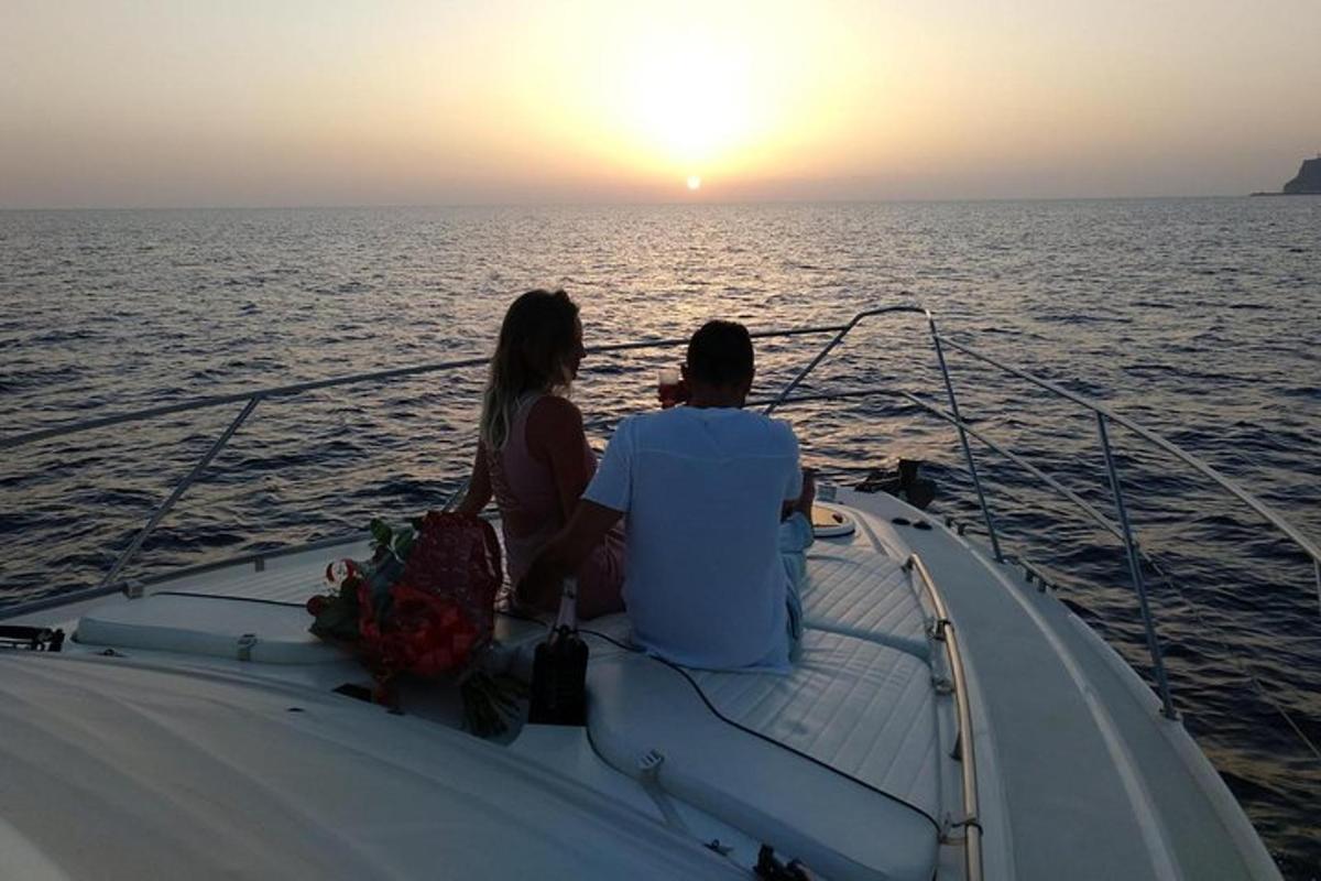 ein Mann und eine Frau sitzen auf einem Boot und beobachten den Sonnenuntergang
