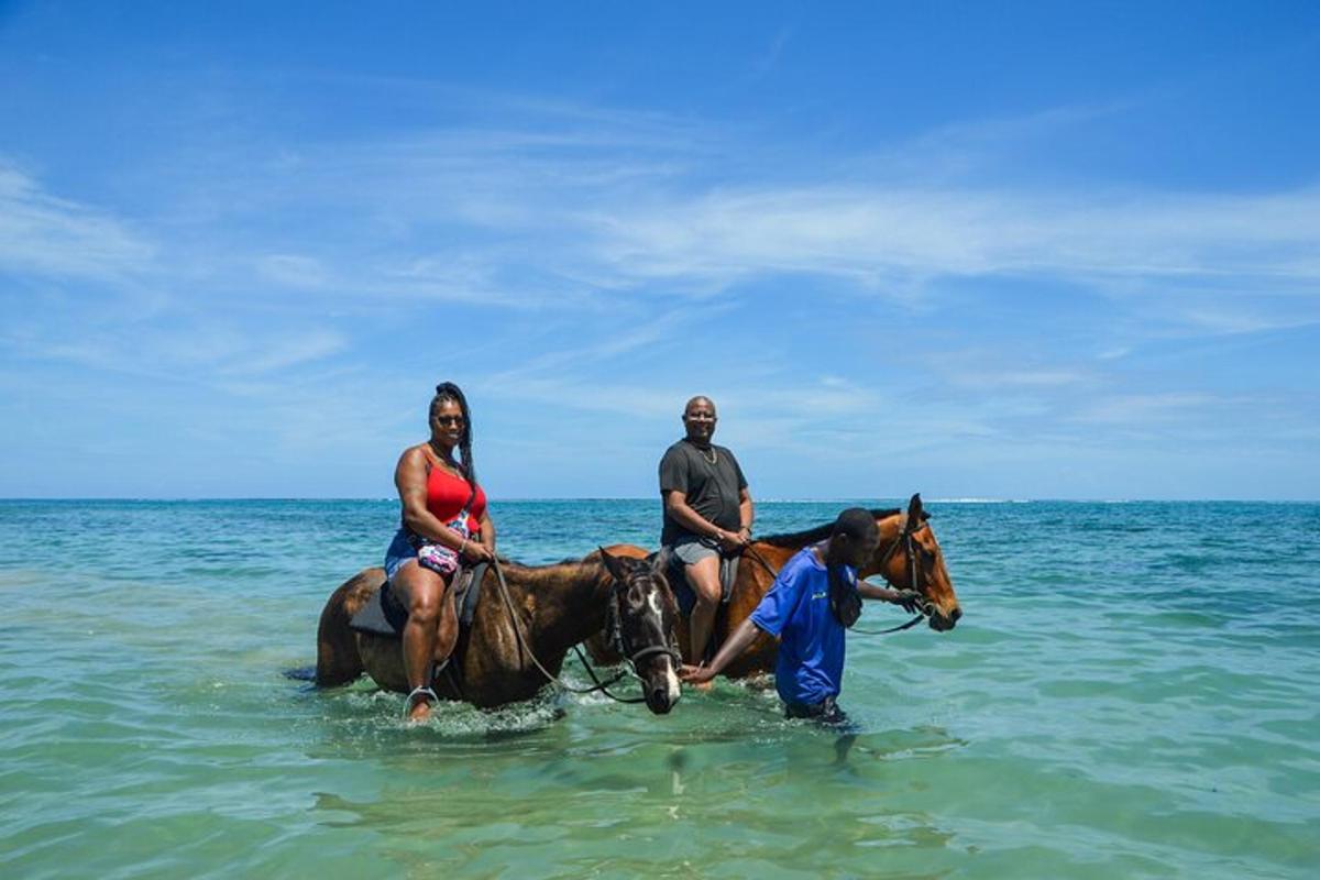 een paar mensen die op paarden in de oceaan rijden