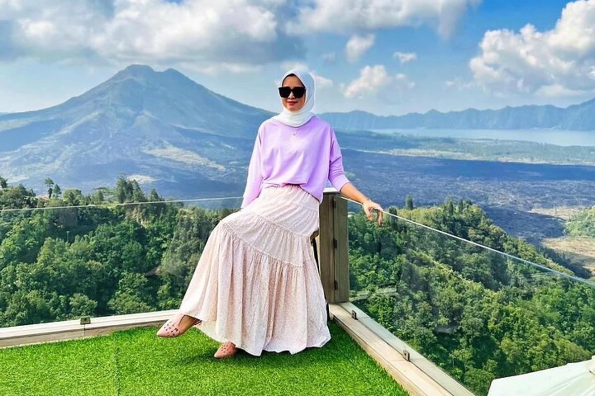 a woman standing on the edge of a ledge with a mountain