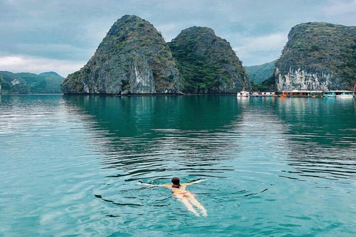 a man swimming in a body of water with mountains