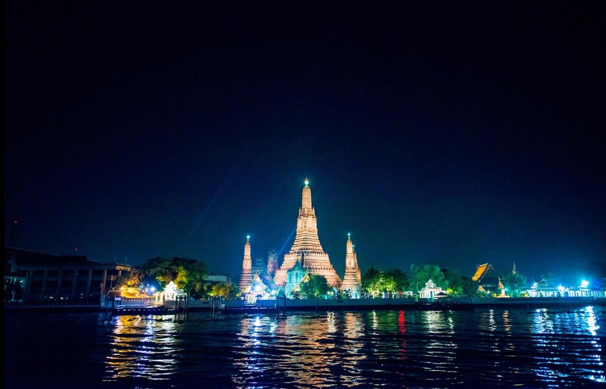 a lit up building at night next to the water