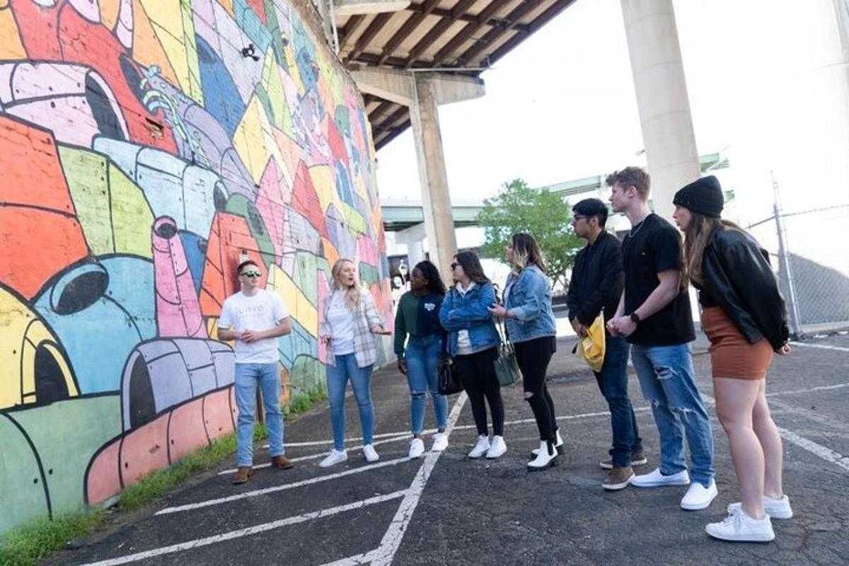 un gruppo di persone in piedi davanti a un murale