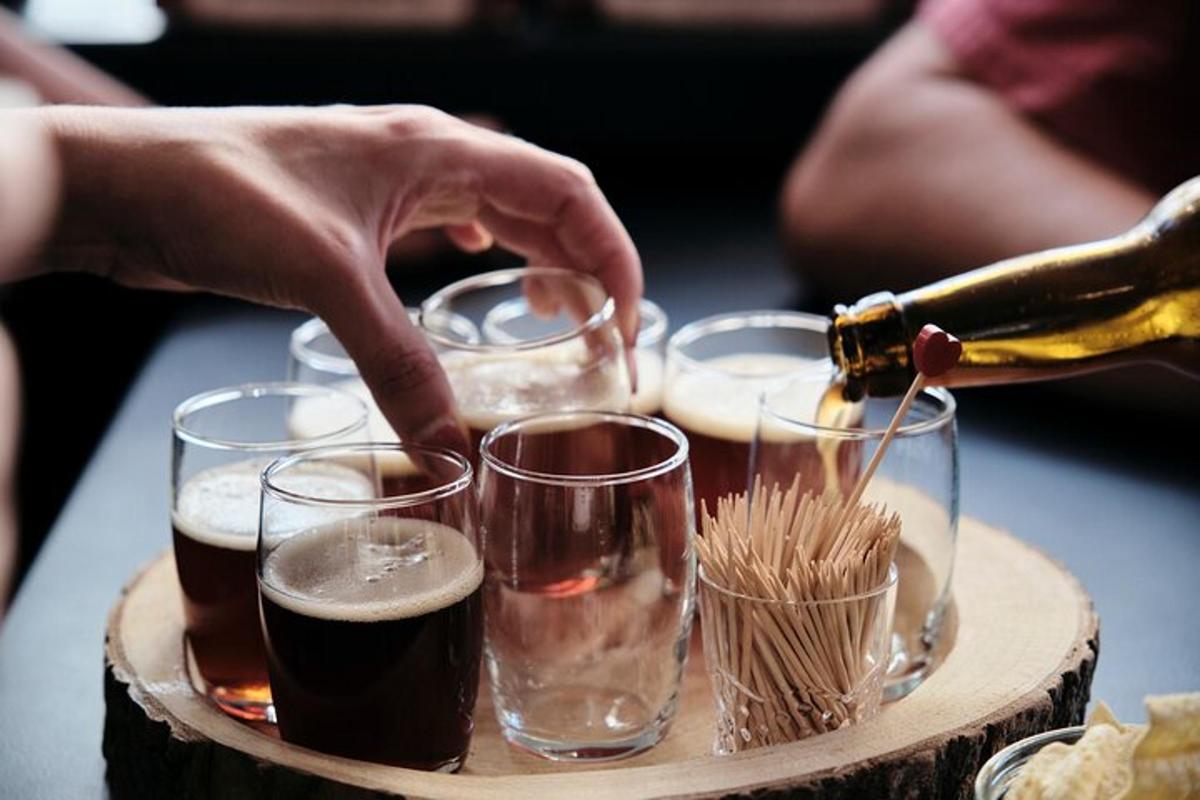 una persona che versa il vino nei bicchieri su un vassoio di legno
