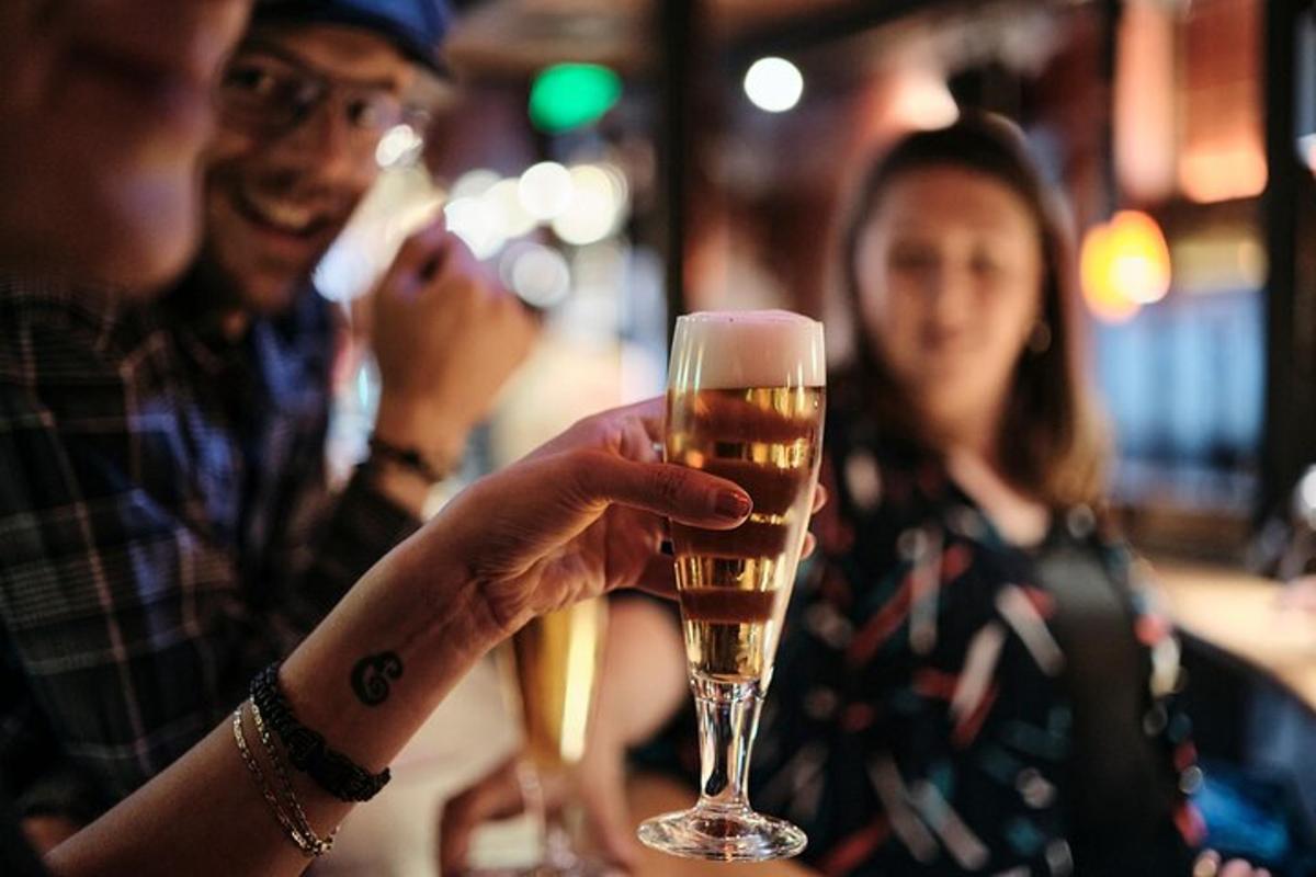 maður heldur á bjórglasi á bar
