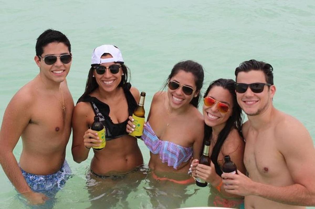 a group of people standing in the water holding beer