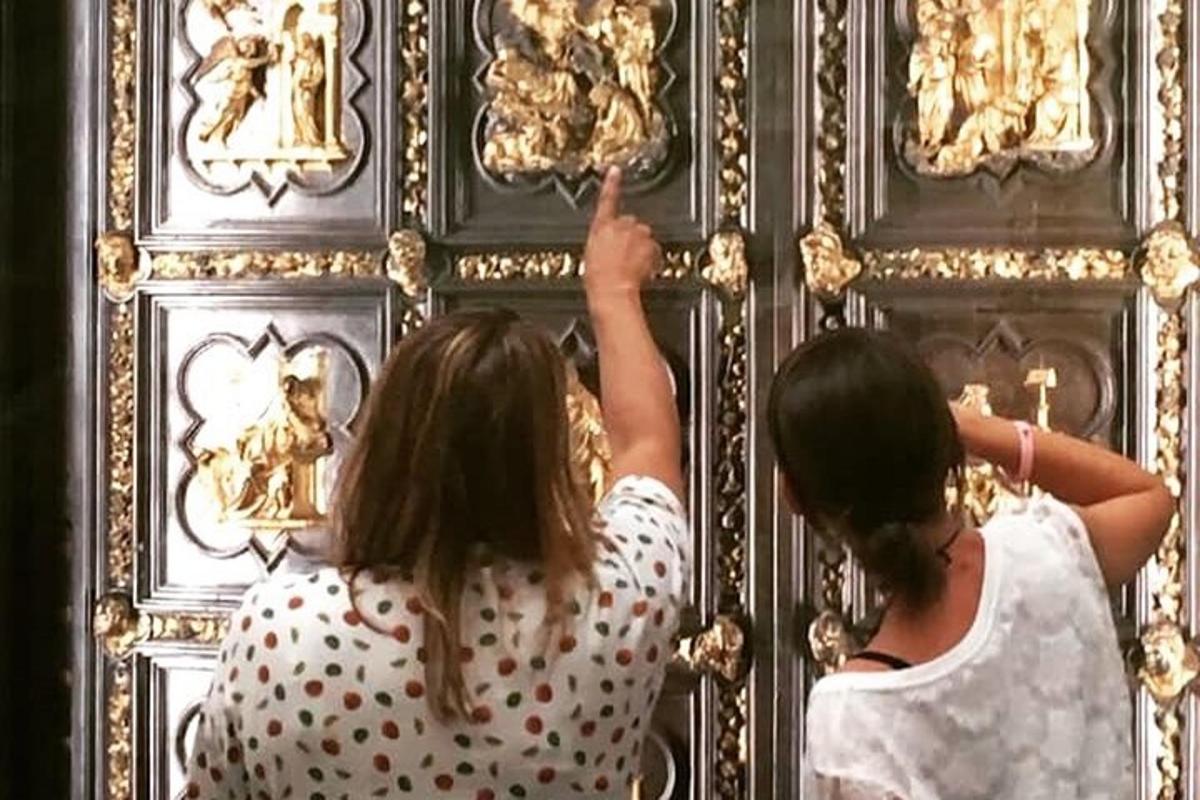 due donne che guardano un muro con delle statue sopra