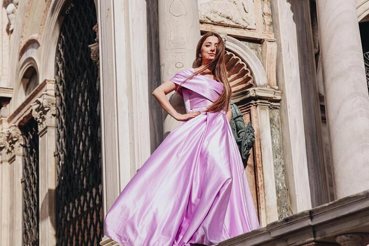 una dona amb un vestit rosa dempeus en un edifici