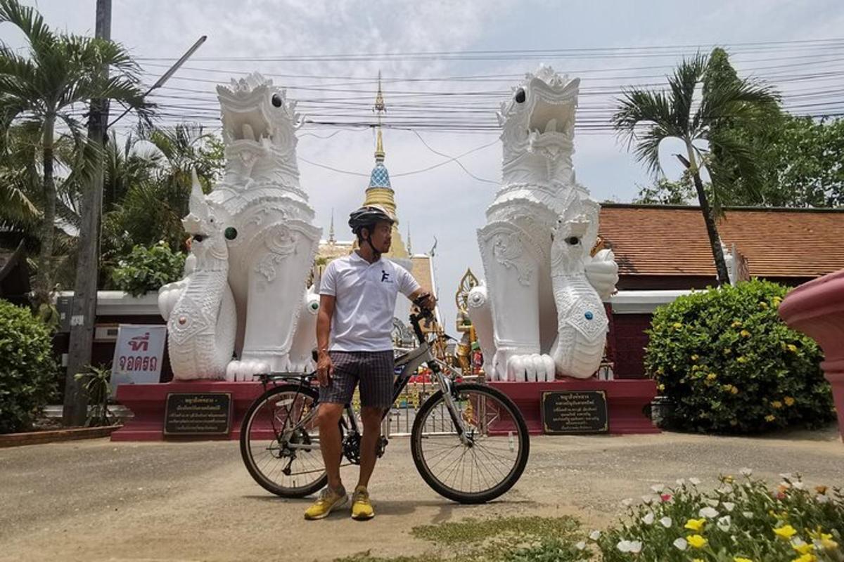 Un hombre parado con una bicicleta frente a un templo.