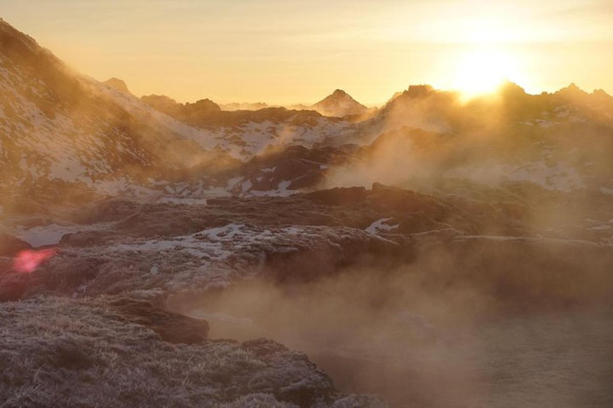 um vale montanhoso enevoado com o sol nascendo atrás das montanhas