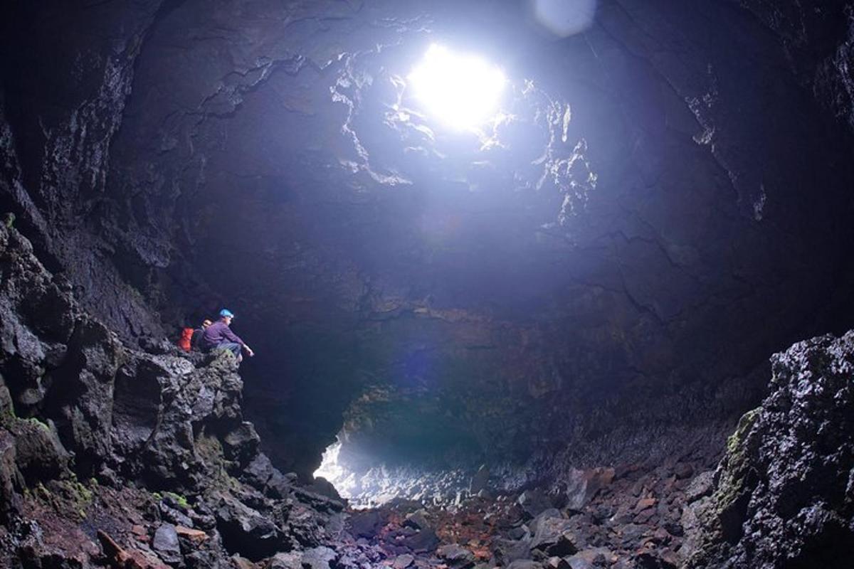 Una persona parada en una cueva con una luz en la parte superior.
