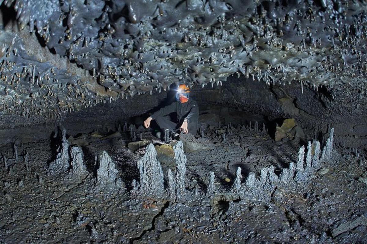 um homem está parado em uma caverna com pedras