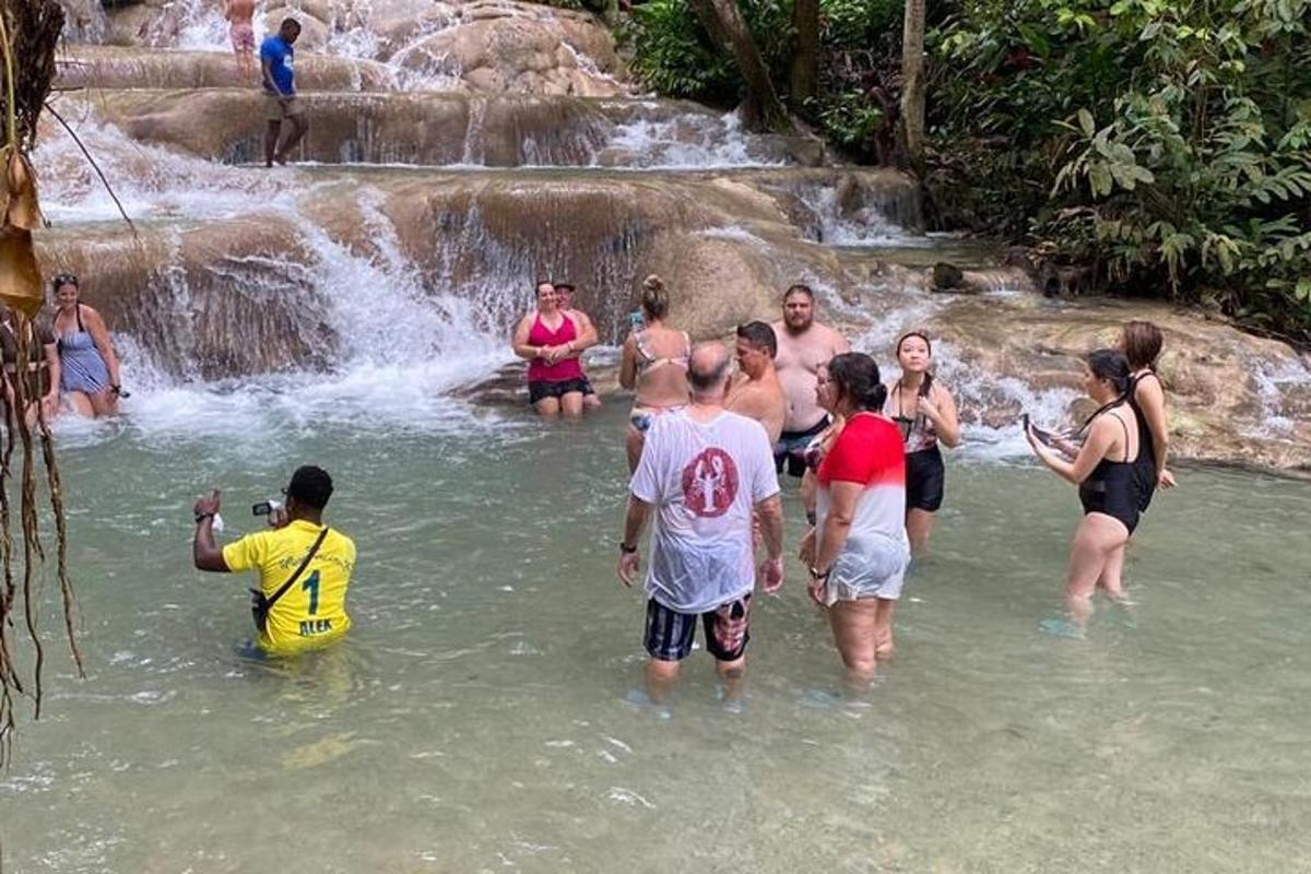 Un grupo de personas de pie en el agua cerca de una cascada.