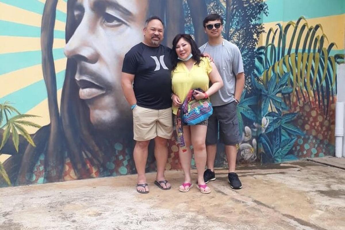 Un grupo de tres personas de pie frente a un mural.