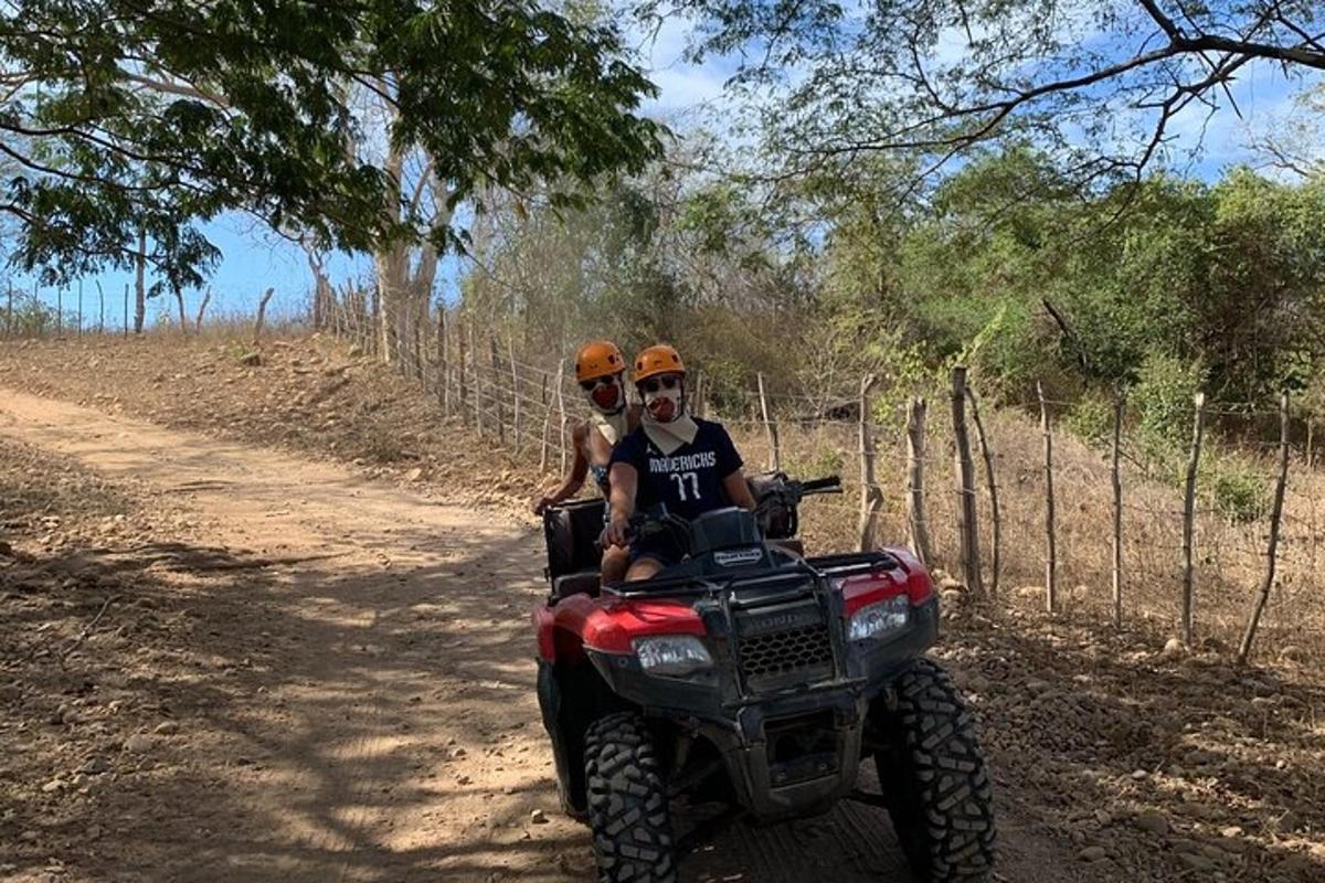 two people riding on a four wheeler on a dirt road