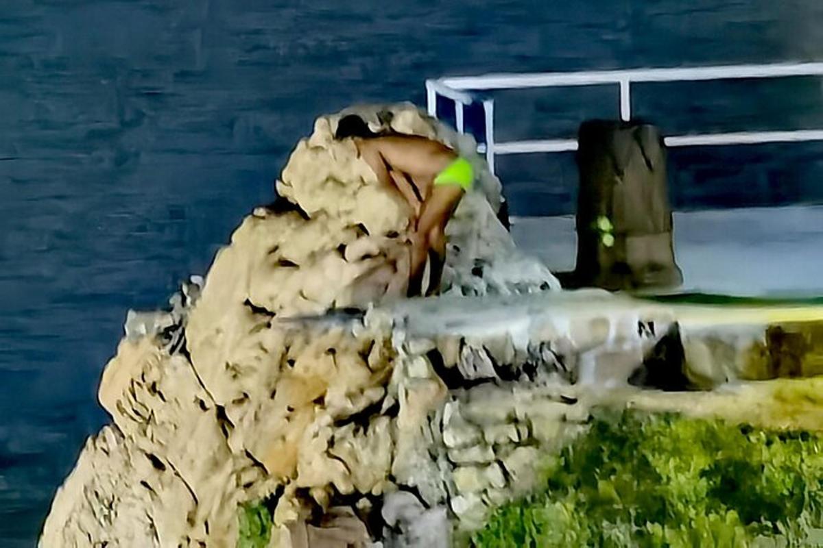 a person sitting on a rock next to the water