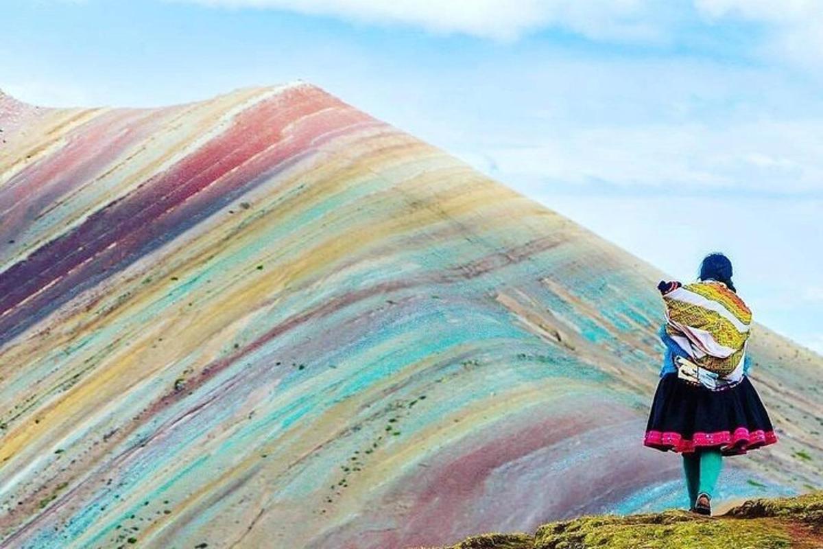 una donna in piedi su una collina con una collina arcobaleno