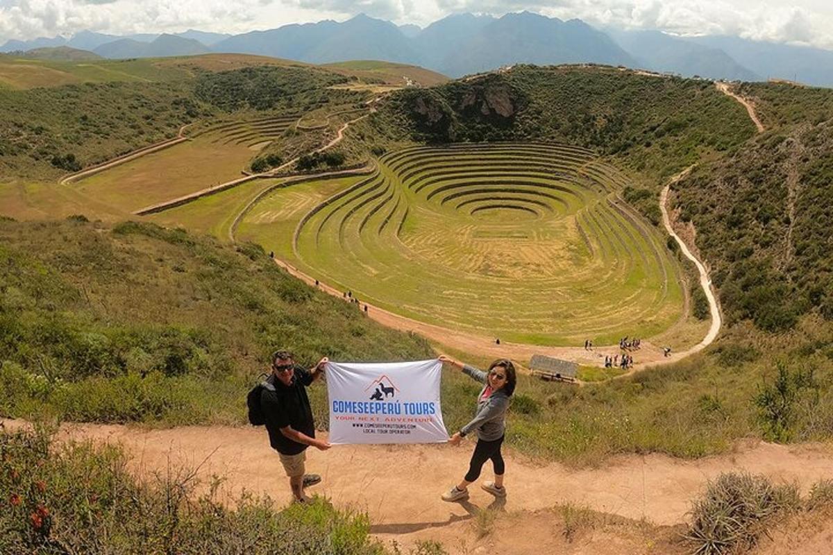 Un hombre y una mujer sosteniendo un cartel frente a un anfiteatro.
