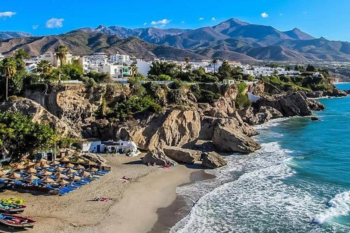 una playa con sombrillas y sillas en una costa rocosa