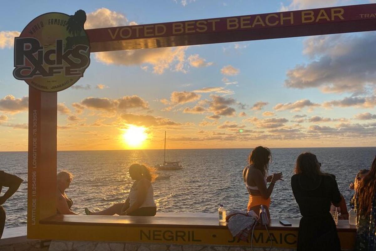 Un grupo de personas viendo la puesta de sol en un chiringuito