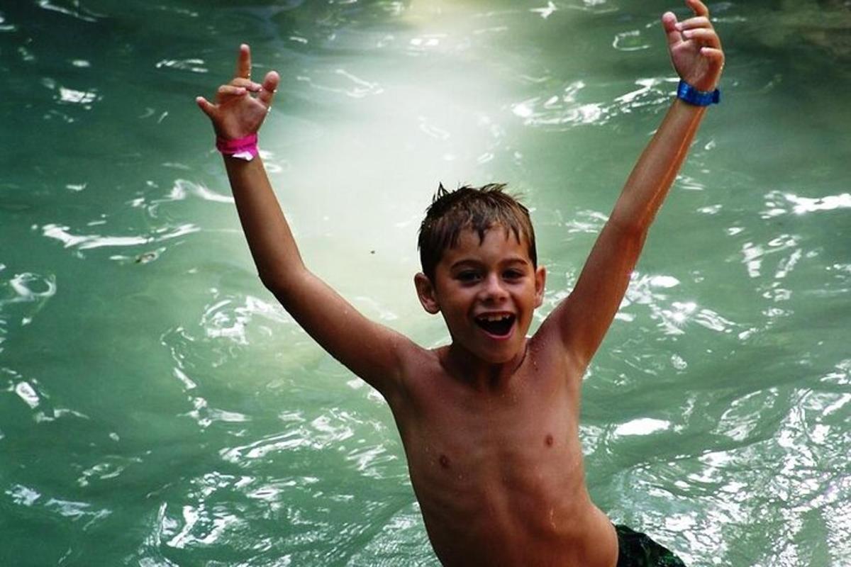 Un niño pequeño en el agua con las manos en el agua.