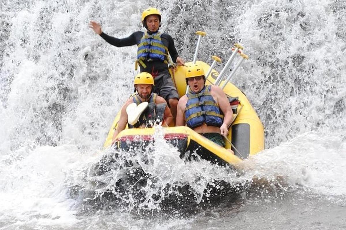 three men in helmets on a raft in a waterfall